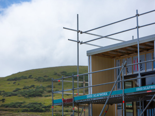 Corner of a house under construction with hills in the background